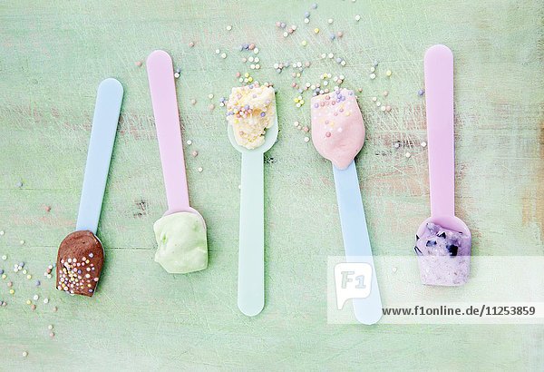 Various types of ice creams on ice cream spoons scattered with sugar pearls: vanilla  strawberry  chocolate  blueberry and mint