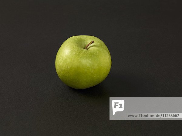Ein grüner Apfel vor schwarzem Hintergrund