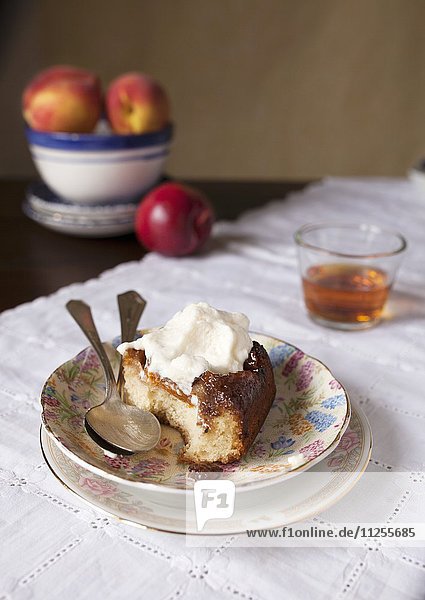 Ein Stück Upside Down Cake (gestürzter Rührkuchen) mit Pfirsichen und Sahne