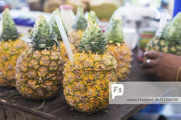 Ananas aufgeschnitten mit Strohhalm auf einem Markt