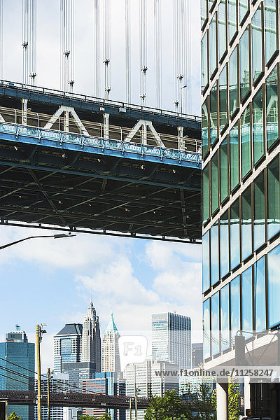 USA  New York State  New York City  Stadtpanorama mit einem Teil der Brooklyn Bridge und der Fassade eines Wolkenkratzers im Vordergrund