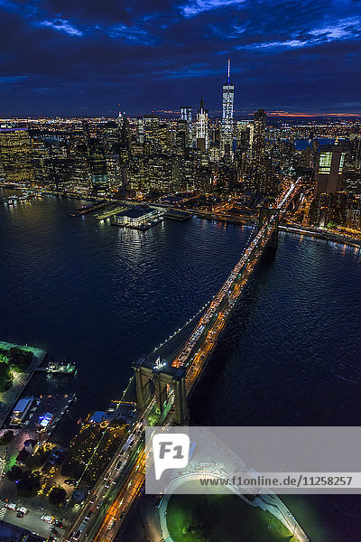 USA  New York  New York City  Manhattan  Luftaufnahme der beleuchteten Skyline mit Hafen und Brooklyn Bridge bei Nacht