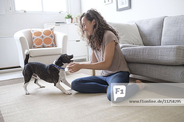 Young woman playing with dog in living room