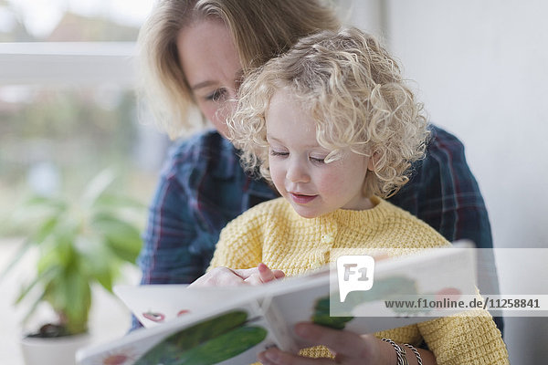 Mother reading book to daughter (4-5)