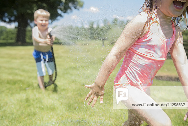 USA  Pennsylvania  Washington Crossing  Boy (4-5) and girl (2-3) playing with water hose