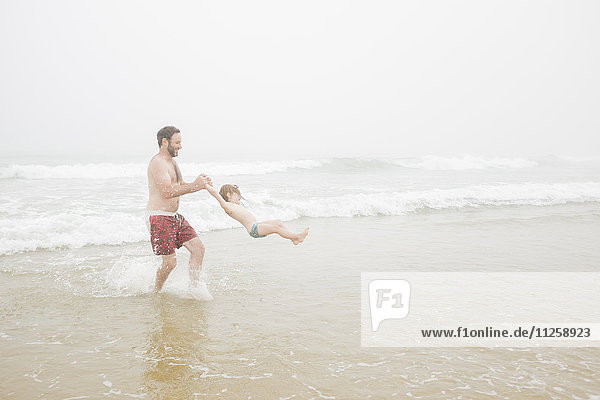 USA  New York  Monatuk  Vater spinnt Tochter (2-3) am Strand am Meer