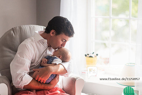 Vater küsst Babysohn (0-1 Monate) am Fenster