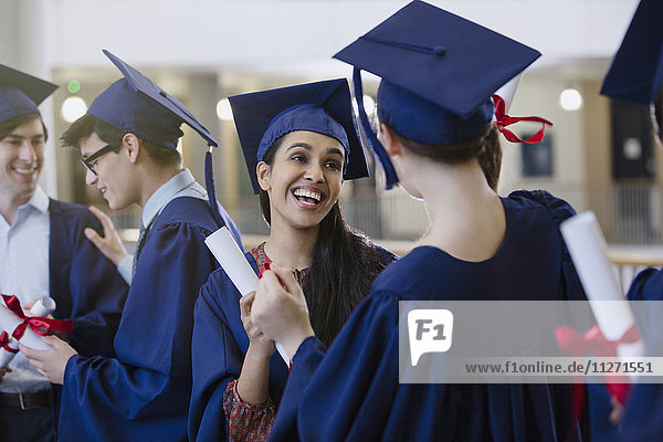 Fröhliche Studentinnen mit Mütze und Kittel und Diplomen beim Feiern
