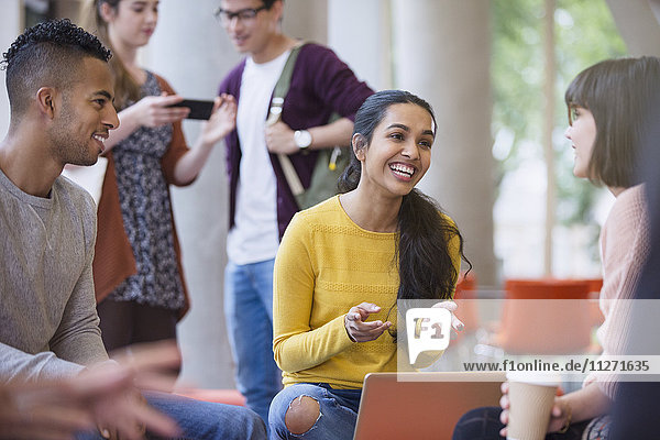 Smiling college students talking and drinking coffee in commons