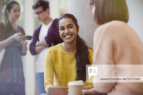 Smiling female college students drinking coffee and talking