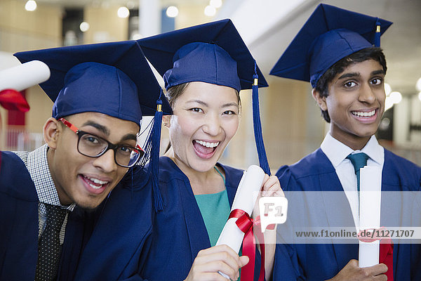 Portrait begeisterte Hochschulabsolventen in Mütze und Kleid mit Diplomen