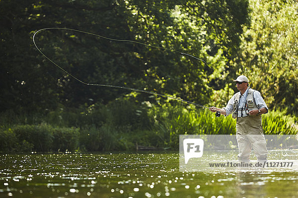Senior man fly fishing at summer river