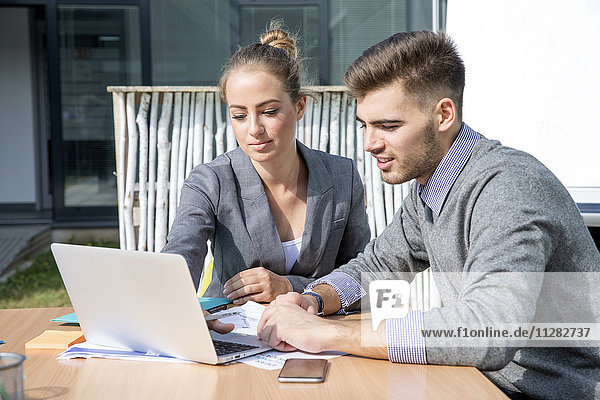 Two business people working on laptop together
