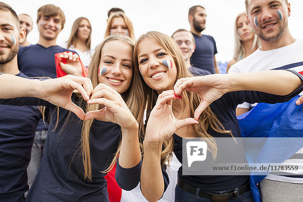 Female soccer fans forming heart with hands
