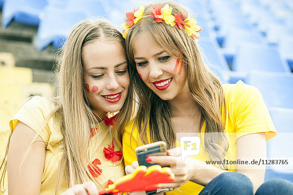Zwei weibliche Fußballfans schreiben sich im Stadion SMS