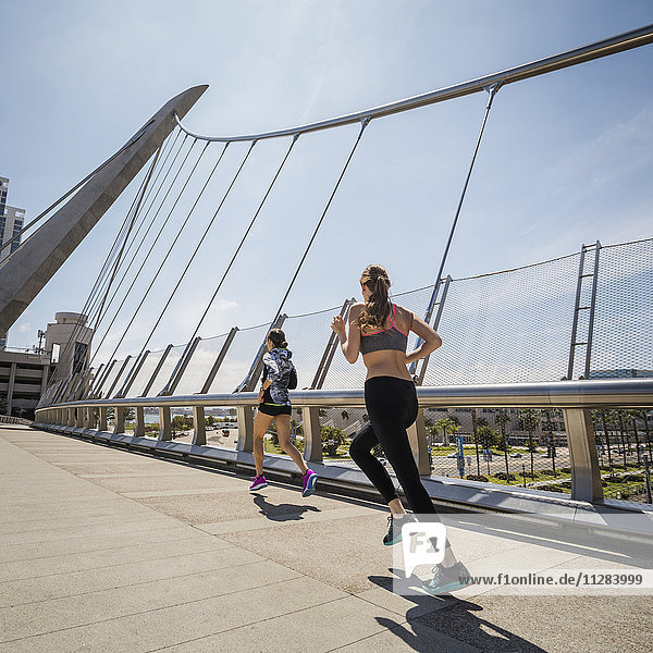 Kaukasische Frauen laufen auf Brücke