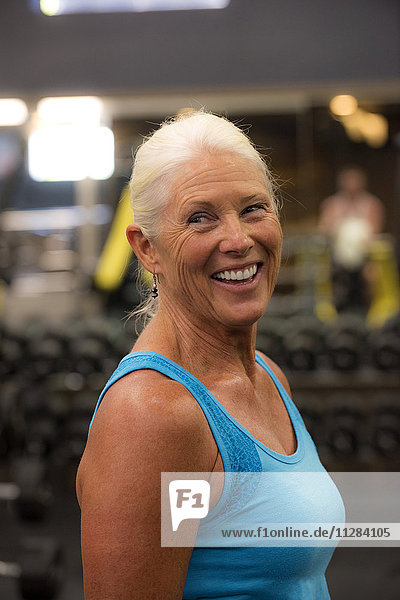 Lächelnde ältere Frau trainiert in einer Turnhalle