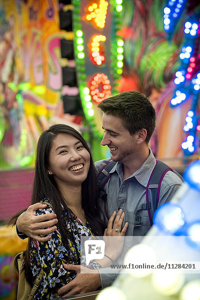 Smiling couple hugging in amusement park