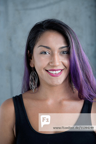 Porträt einer lächelnden hispanischen Frau mit lila Haaren