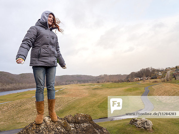 Kaukasisches Mädchen steht auf einem Felsen im Wind