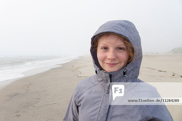 Portrait of smiling Caucasian girl on cold beach
