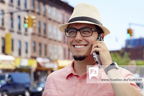 Hispanischer Mann  der in der Stadt mit einem Handy telefoniert