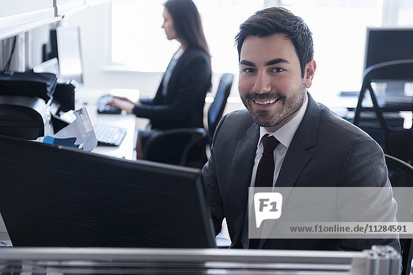 Porträt eines lächelnden Geschäftsmannes  der einen Computer im Büro benutzt