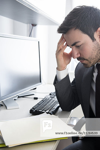 Businessman with headache at office desk