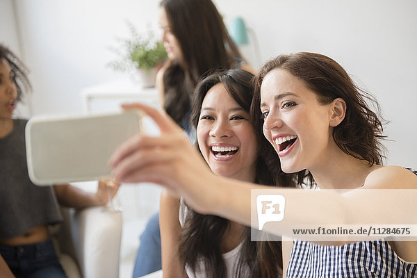 Lächelnde Frauen  die für ein Handy-Selfie auf einer Party posieren