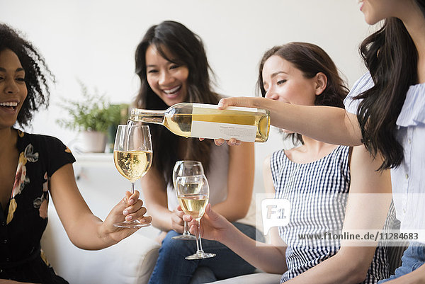 Frau schenkt eine Flasche Weißwein für Freunde ein