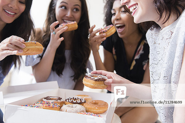 Smiling women eating donuts