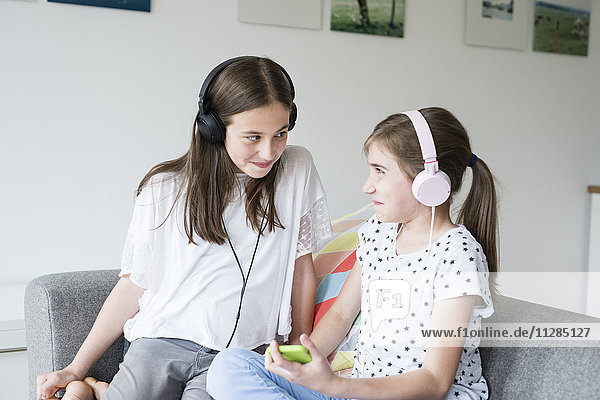 Two teenage girls with headphones listening to music
