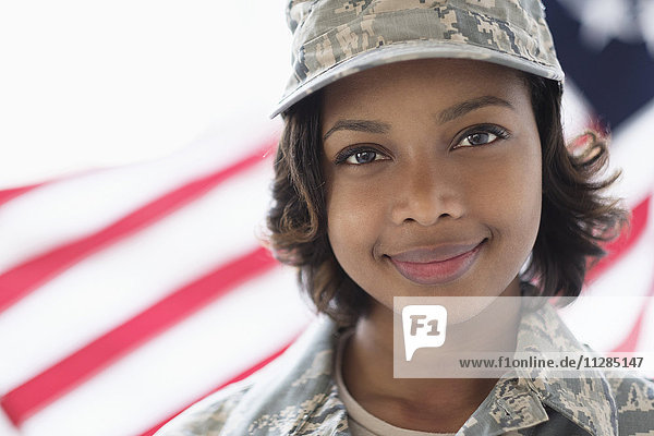 Porträt eines lächelnden gemischtrassigen Soldaten in der Nähe der amerikanischen Flagge