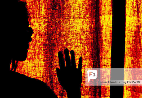 Silhouette einer japanischen Frau vor einem orangefarbenen Vorhang
