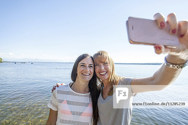 Zwei junge Frauen machen ein Selfie am See