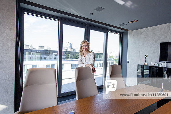 Geschäftsfrau im Sitzungssaal lehnt sich gegen einen Bürostuhl