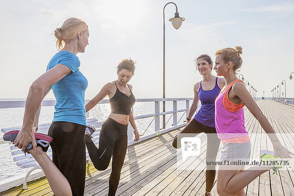 Group of women stretching legs on jetty