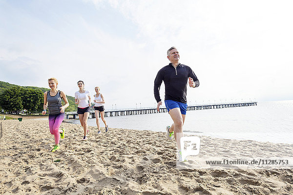 Group of friends jogging on beach