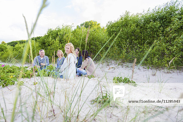 Group of friends sitting on sandy beach