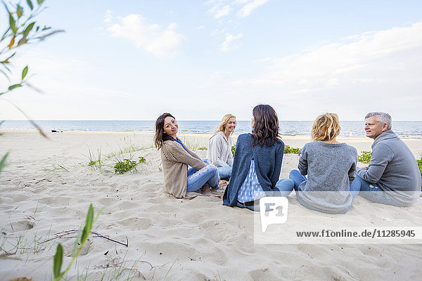 Gruppe von Freunden sitzt am Sandstrand