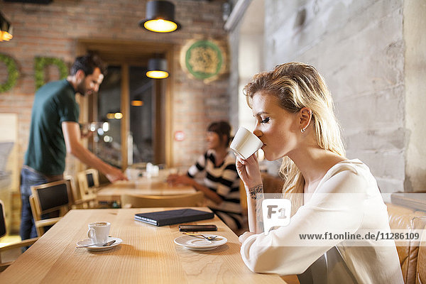 Woman with blond hair drinking espresso in coffee shop