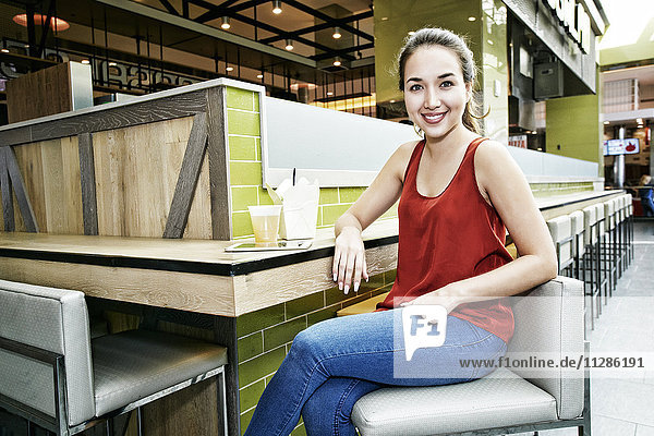 Lächelnde gemischtrassige Frau posiert im Food Court