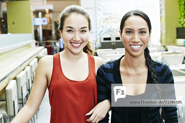 Lächelnde Mixed-Race-Frauen posieren im Food Court