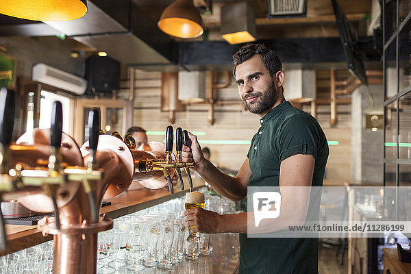 Barkeeper in einem Café schenkt Bier aus dem Zapfhahn ein