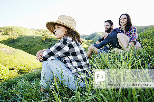 Familie sitzt auf einem Hügel und schaut weg