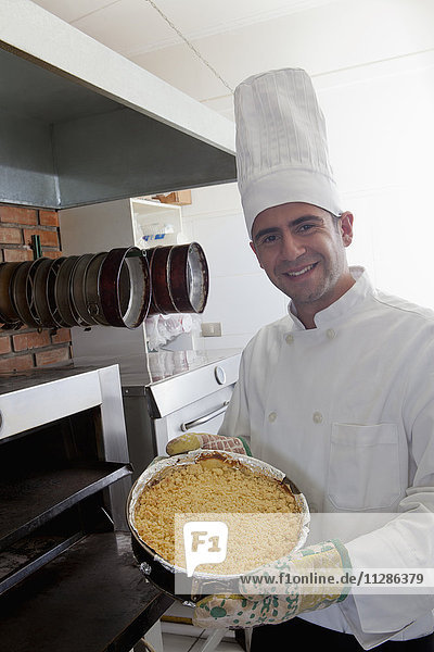 Hispanic chef holding cheesecake near oven