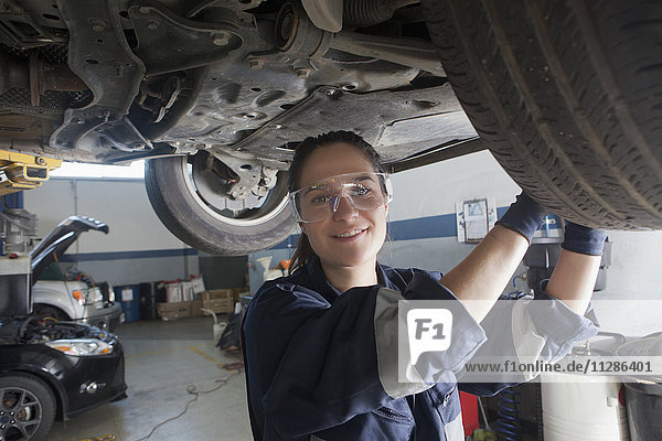 Smiling Hispanic mechanic repairing car