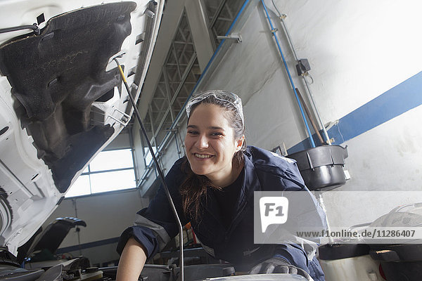 Smiling Hispanic mechanic repairing car engine