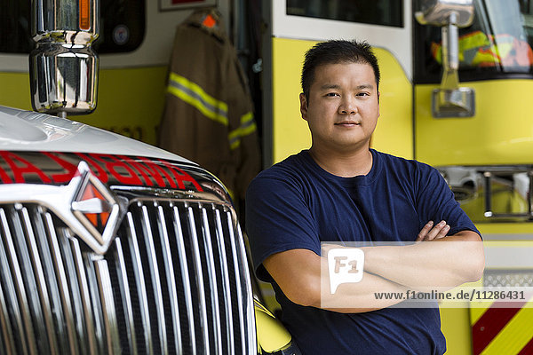 Ernster chinesischer Feuerwehrmann posiert mit Feuerwehrauto