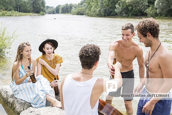 Group of friends drinking beer on the riverbank